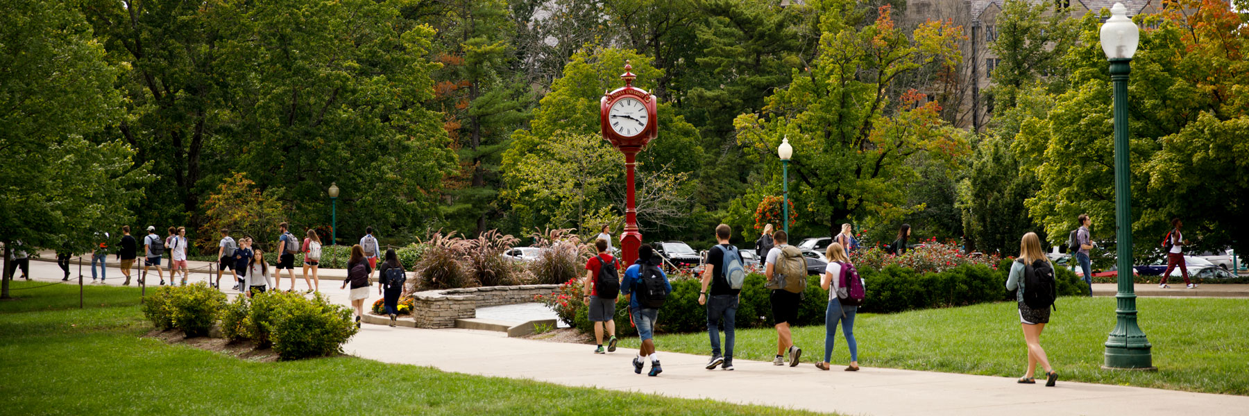 students walking on campus near an outdoor clock